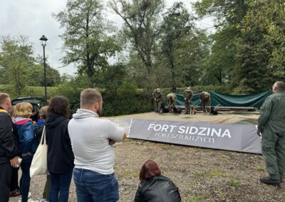 psi pokaz - pieski siedzą przy wojskowych i czekają na polecenia